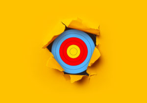 Bright yellow torn paper cardboard inside a hole colored target.